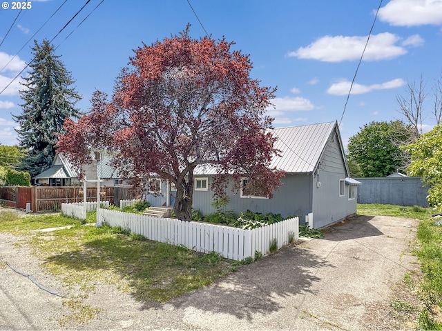 view of side of property featuring metal roof and a fenced front yard