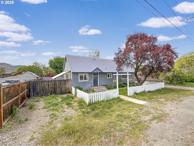 rear view of property featuring a fenced front yard and metal roof