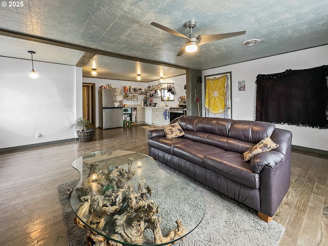 living area featuring indoor bar, visible vents, hardwood / wood-style floors, a textured ceiling, and baseboards