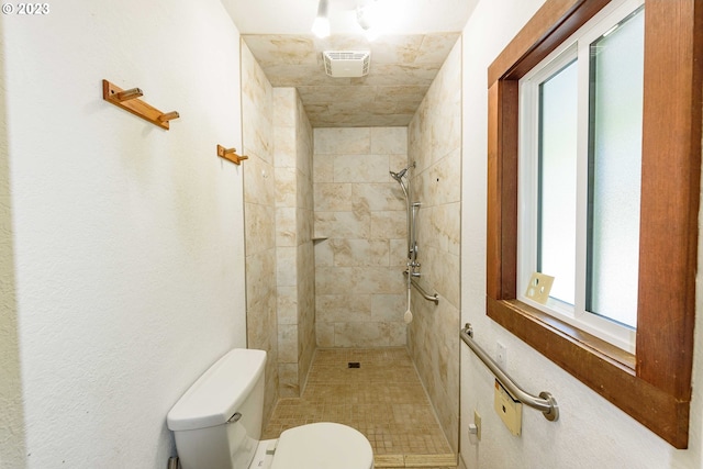 bathroom with tiled shower and toilet