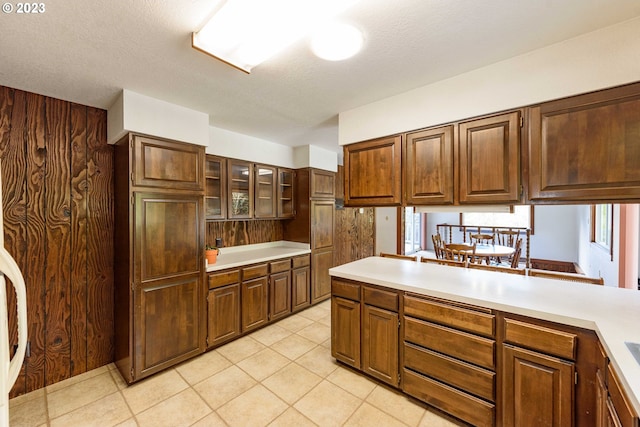 kitchen featuring light tile patterned floors, a textured ceiling, and kitchen peninsula