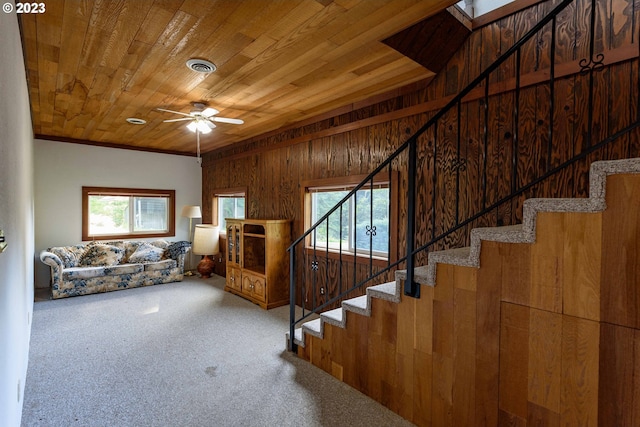 unfurnished living room with wood ceiling, carpet flooring, wooden walls, and ceiling fan