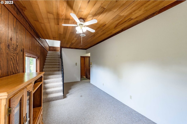 unfurnished living room featuring wood ceiling, ceiling fan, carpet, and wood walls