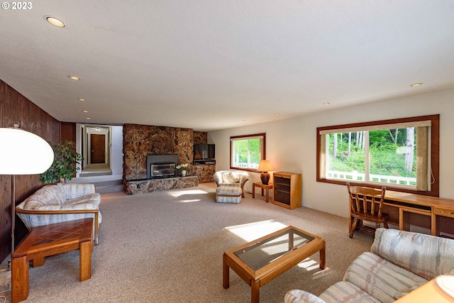 living room featuring wooden walls, light colored carpet, and a stone fireplace