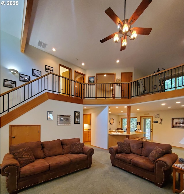 living area with stairs, carpet flooring, visible vents, and a towering ceiling