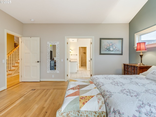 bedroom featuring wood finished floors, baseboards, and ensuite bathroom