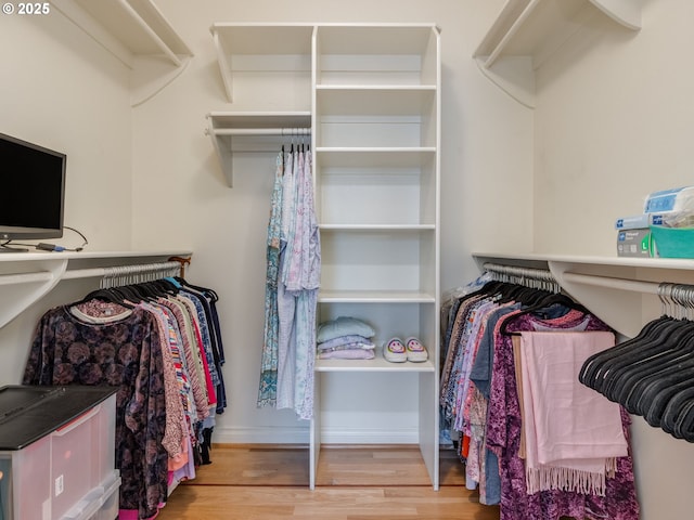 walk in closet with wood finished floors and built in desk