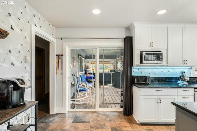 7655 Elliott St, Bay City, OR 97107 - kitchen featuring stainless steel microwave, dark stone countertops, recessed lighting, white cabinets, and stone finish floor