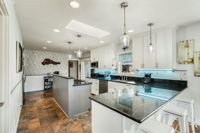 7655 Elliott St, Bay City, OR 97107 - kitchen with stone finish floor, a skylight, appliances with stainless steel finishes, a center island, and a sink