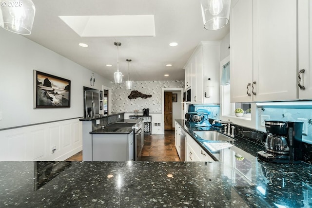 7655 Elliott St, Bay City, OR 97107 - kitchen featuring dark stone countertops, a sink, stainless steel appliances, a skylight, and a kitchen island