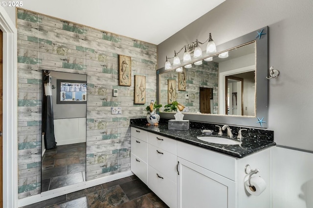 7655 Elliott St, Bay City, OR 97107 - bathroom featuring stone tile floors, wooden walls, and vanity