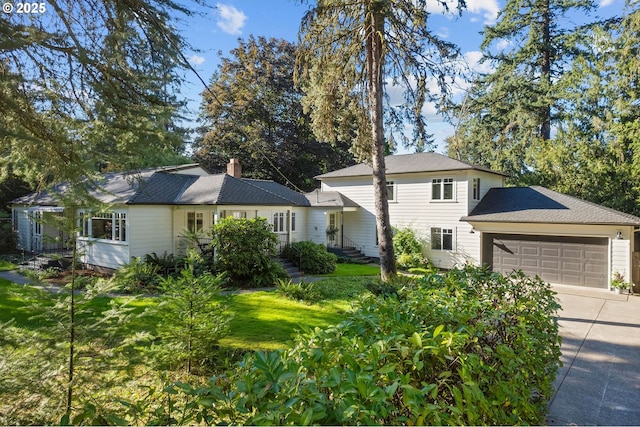 view of front of property featuring a garage, driveway, a chimney, and a front lawn