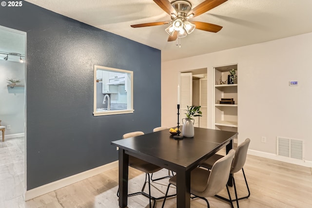 7573 N Edgewater Ave, Portland, OR 97203 - dining area featuring built in features, a ceiling fan, light wood-style floors, and baseboards