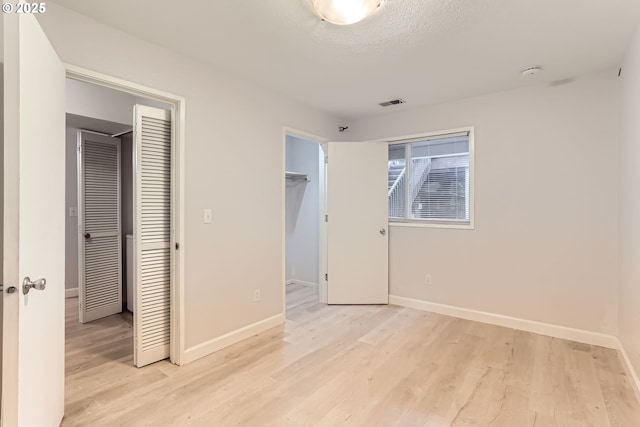 7573 N Edgewater Ave, Portland, OR 97203 - unfurnished bedroom featuring light wood finished floors, baseboards, a walk in closet, and a closet