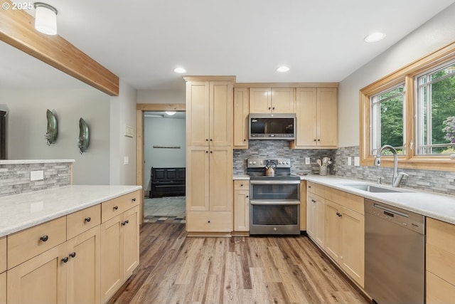 24601 SW 65th Ave, Tualatin, OR 97062 - kitchen with stainless steel appliances, light brown cabinets, a sink, light wood finished floors, and backsplash