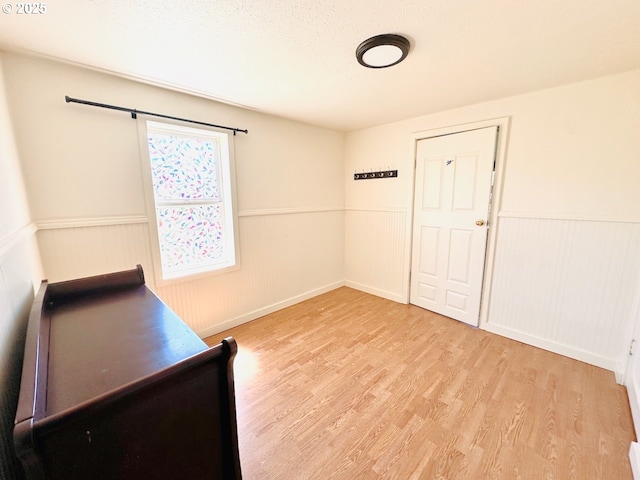 unfurnished bedroom with wood finished floors and wainscoting