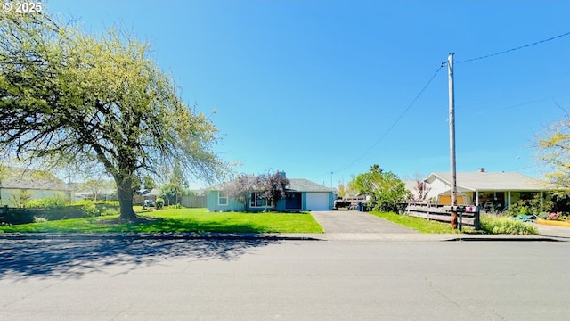 view of front of home featuring an attached garage, driveway, fence, and a front lawn