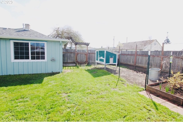 view of yard featuring a fenced backyard, an outdoor structure, exterior structure, and a vegetable garden