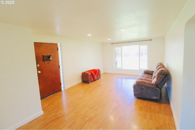 sitting room with arched walkways, baseboards, light wood-style floors, and recessed lighting