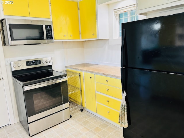 kitchen featuring stainless steel appliances, light countertops, and yellow cabinetry