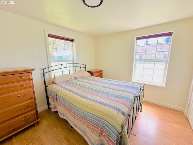 bedroom featuring baseboards and light wood finished floors
