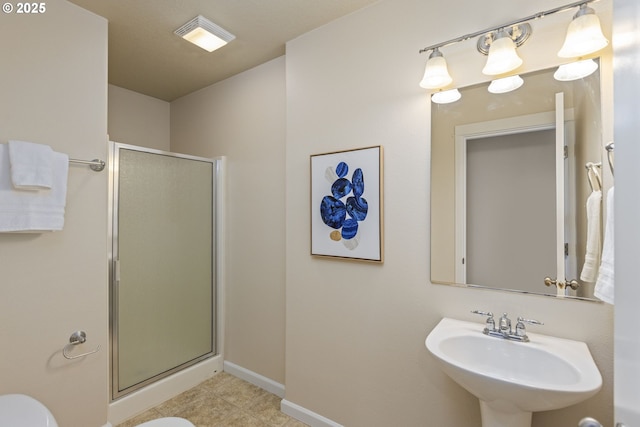 bathroom with toilet, sink, and a shower with shower door