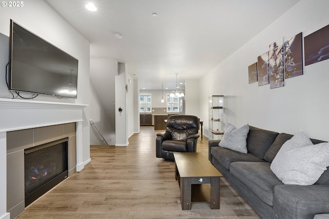 living room with baseboards, a tiled fireplace, and light wood finished floors