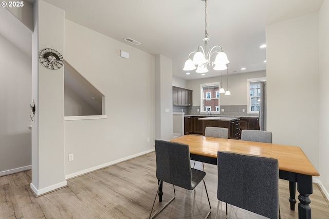 dining space with baseboards, visible vents, light wood finished floors, an inviting chandelier, and recessed lighting