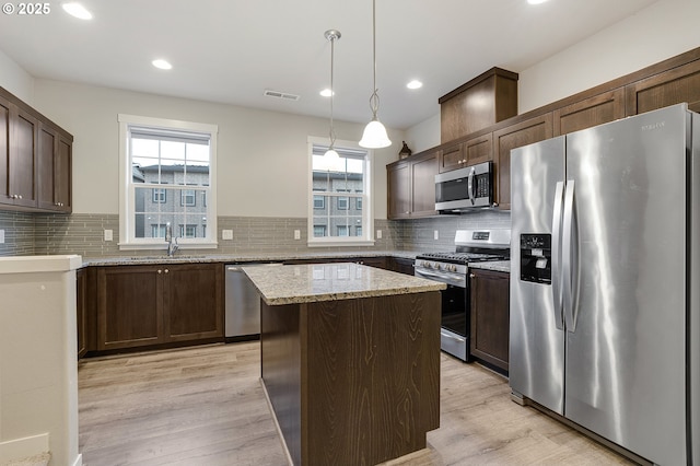 kitchen featuring visible vents, light stone countertops, light wood-type flooring, appliances with stainless steel finishes, and a sink