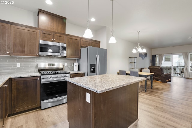 kitchen featuring backsplash, a kitchen island, dark brown cabinetry, light wood-type flooring, and appliances with stainless steel finishes