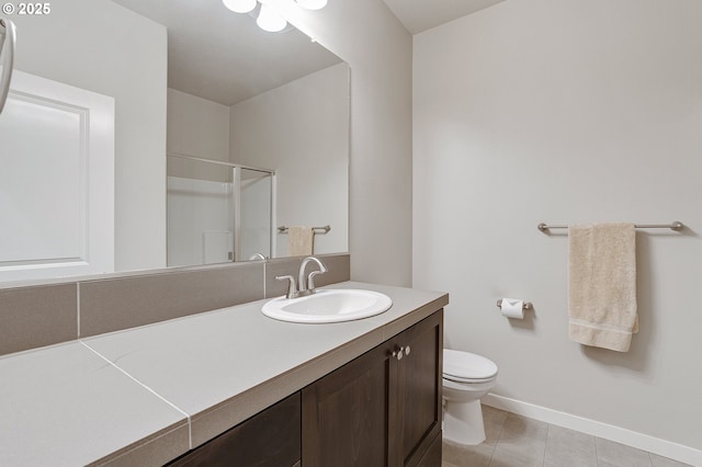 bathroom featuring baseboards, toilet, a stall shower, tile patterned floors, and vanity