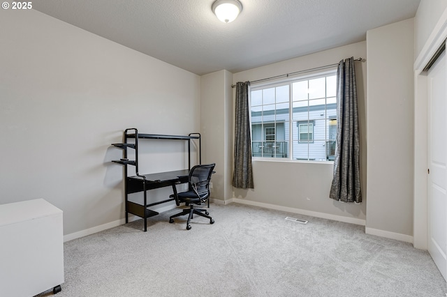 carpeted office space with visible vents, baseboards, and a textured ceiling