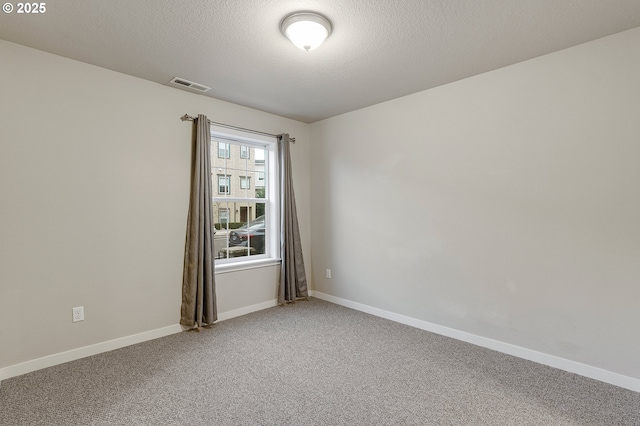 empty room featuring visible vents, baseboards, light colored carpet, and a textured ceiling