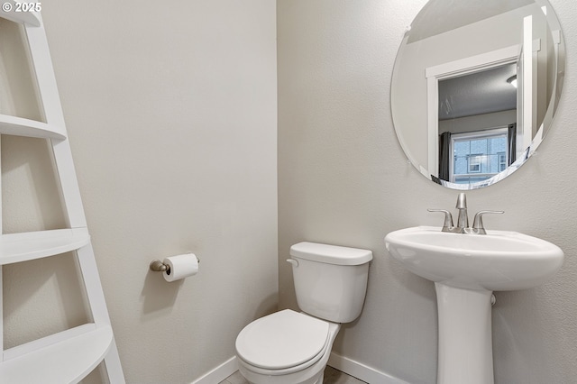 bathroom featuring a sink, baseboards, and toilet