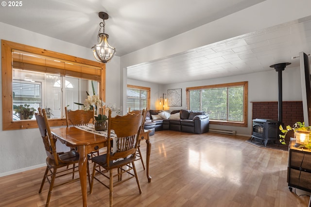 1175 Northside Rd, Sutherlin, OR 97479 - dining room with a wood stove, wood finished floors, a chandelier, baseboards, and baseboard heating