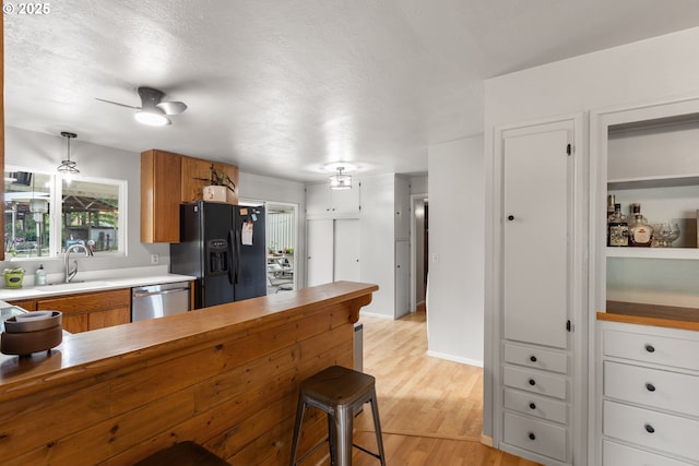 1175 Northside Rd, Sutherlin, OR 97479 - kitchen with black fridge, stainless steel dishwasher, brown cabinets, light wood-style flooring, and a sink