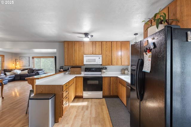 1175 Northside Rd, Sutherlin, OR 97479 - kitchen with black fridge with ice dispenser, white microwave, electric range, a peninsula, and light wood-type flooring