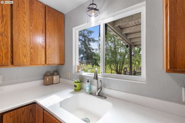 1175 Northside Rd, Sutherlin, OR 97479 - kitchen with a sink, light countertops, a textured wall, brown cabinets, and decorative light fixtures