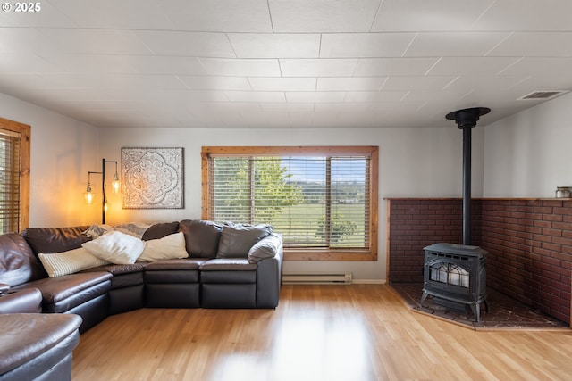 1175 Northside Rd, Sutherlin, OR 97479 - living room with a baseboard radiator, a wood stove, light wood-style flooring, and baseboards