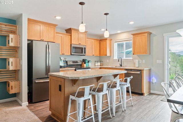 kitchen with a kitchen island, appliances with stainless steel finishes, decorative light fixtures, sink, and light brown cabinets