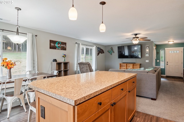 kitchen with ceiling fan, a center island, pendant lighting, and dark wood-type flooring