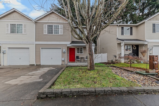 view of front facade featuring a front yard, an attached garage, driveway, and fence