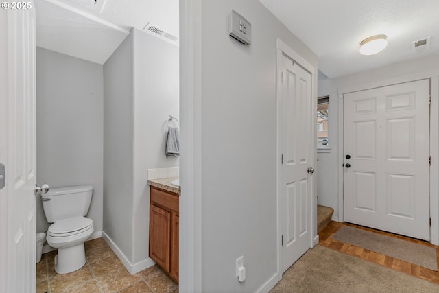 bathroom featuring visible vents, toilet, vanity, and baseboards