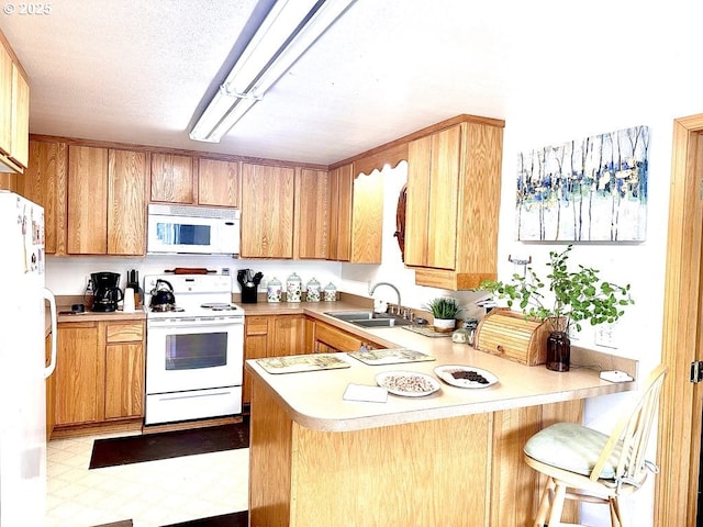 1021 Starlight St, The Dalles, OR 97058 - kitchen with white appliances, a peninsula, a sink, tile patterned floors, and light countertops
