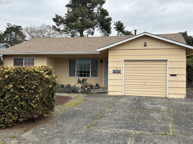 view of front facade featuring concrete driveway, an attached garage, and a shingled roof