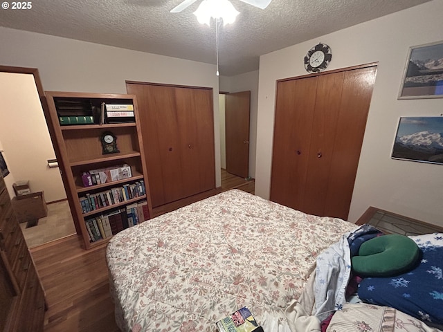 bedroom with ceiling fan, dark wood-type flooring, and a textured ceiling