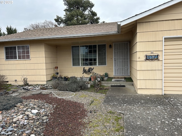 view of exterior entry featuring crawl space and a shingled roof