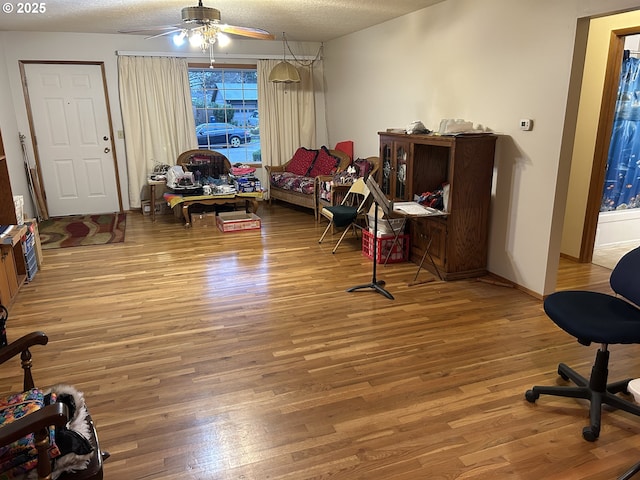 living area featuring ceiling fan, hardwood / wood-style floors, and a textured ceiling