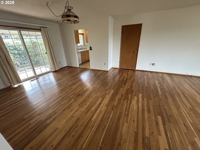 spare room featuring dark wood-style floors, visible vents, and baseboards