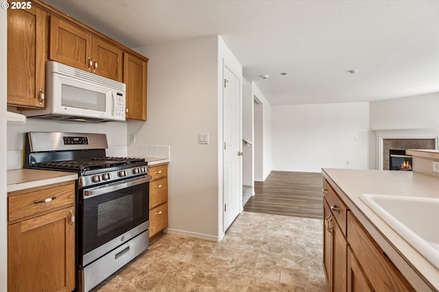 kitchen featuring a fireplace, stainless steel gas range, and sink